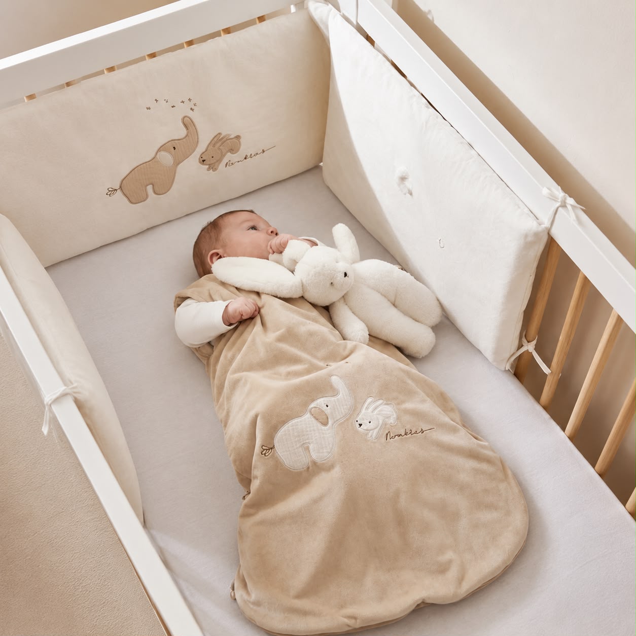 Een baby ligt in de noukies baby slaapzak in de kleur beige